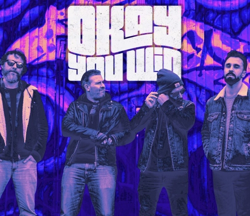 Okay You Win — the four-piece photographed against a purple graffiti backdrop, band logo overhead